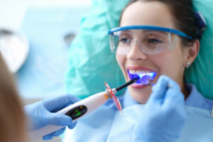 Female patient with UV wand in mouth during dental bonding treatment