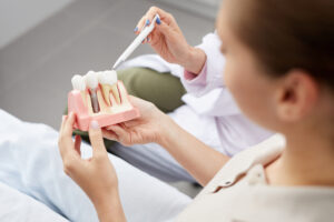Dentist showing tooth implant model to female patient